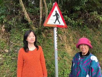 Portrait of senior woman with daughter standing by pedestrian sign