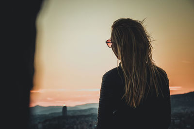 Rear view of woman standing against sea at sunset