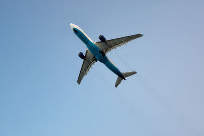 Low angle view of airplane against clear blue sky