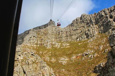 Low angle view of overhead cable car against rocky mountains