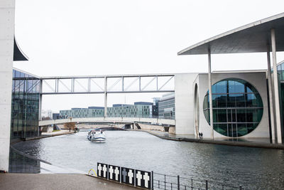 Bridge over river by buildings against sky