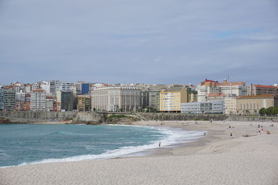 Scenic view of beach by buildings against sky