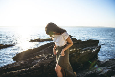 Young latina woman exploring by the ocean at golden hour in summertime