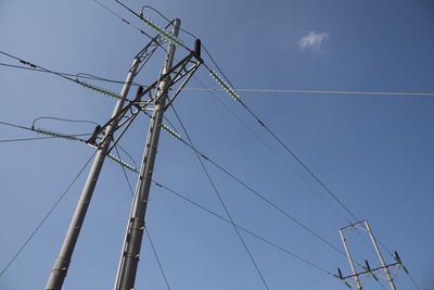 Low angle view of electricity pylon against clear blue sky