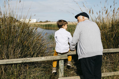 Back view of little boy and his grandfather looking at each other