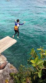 Rear view of woman jumping in sea