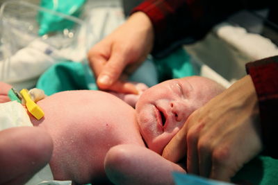 Cropped image of woman touching newborn baby at hospital