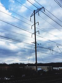 Low angle view of electricity pylon against cloudy sky