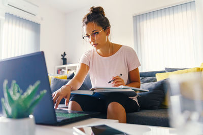 Woman using phone while sitting on table