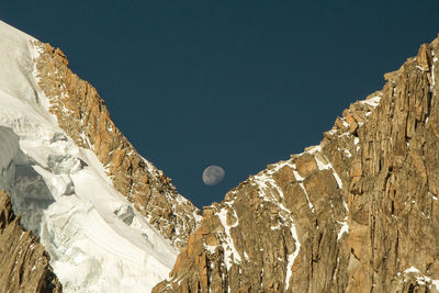 Idyllic shot of moon over rocky mountains against clear sky
