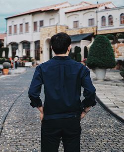 Rear view of man standing on footpath in city