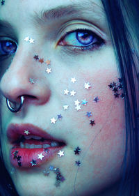 Close-up portrait of woman with star shape glitters on face