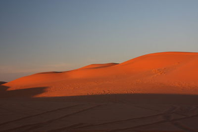 Scenic view of desert against clear sky during sunset