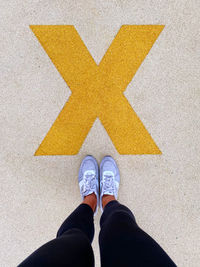 Low section of man standing on arrow sign