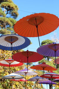 Low angle view of multi colored umbrellas hanging against sky