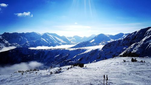 Scenic view of snow covered mountains against blue sky