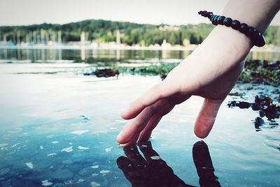 Low section of mans hand in lake