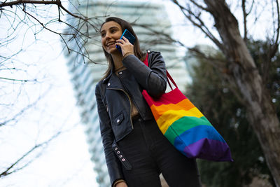 Beautiful lesbian woman with a pride bag talking on the phone.