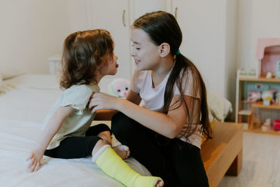 Two girls are fooling around while sitting on the bed in the morning.