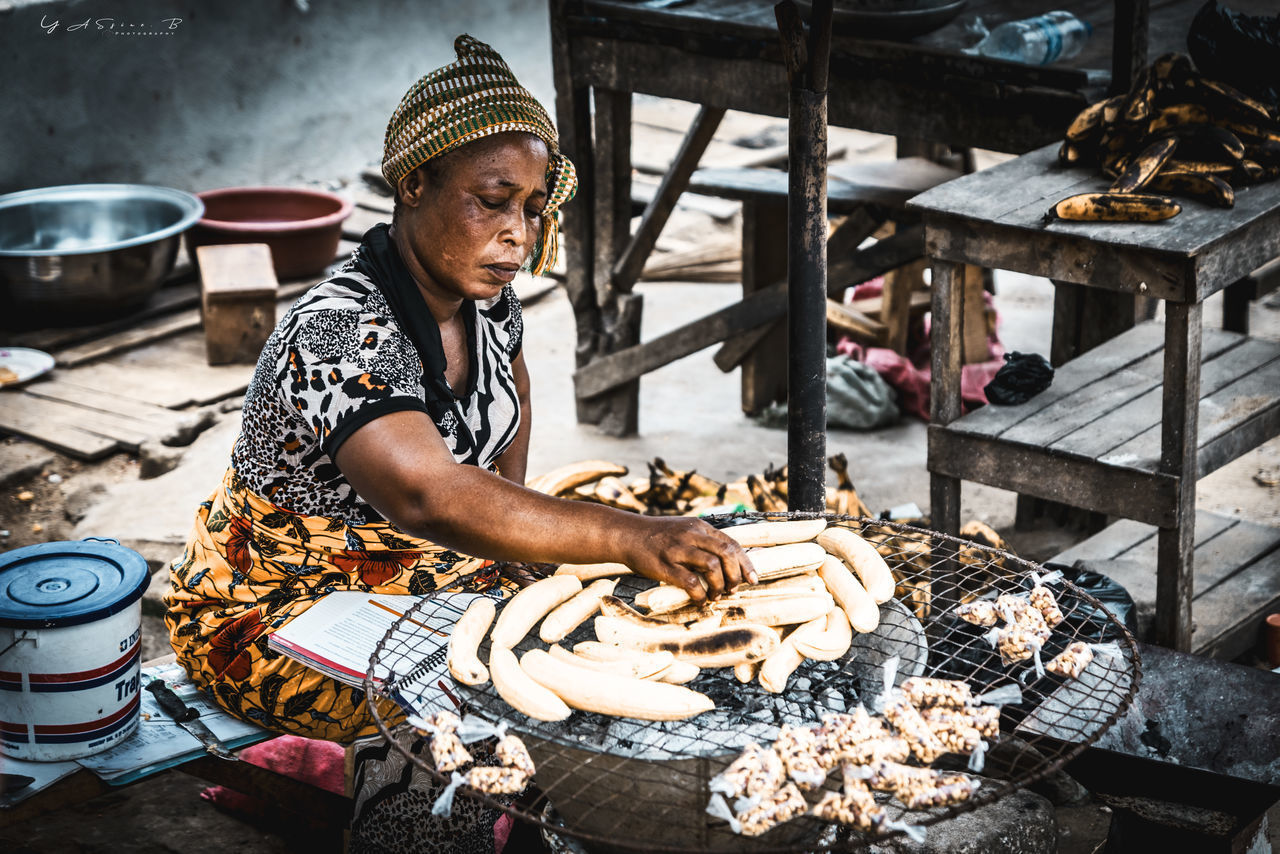 FULL LENGTH OF WOMAN PREPARING FOOD AT MARKET