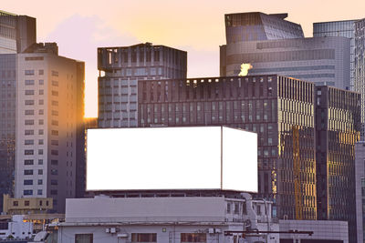 Modern buildings in city against sky during sunset