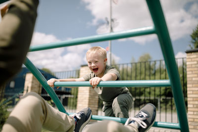 Boy with down syndrome and father at jungle gym in park