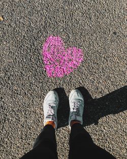 Low section of woman standing by pink heart shape on road