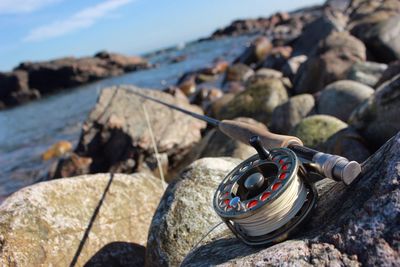 Close-up of fishing rod on rocks by river