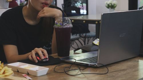 Midsection of man using mobile phone while sitting on table