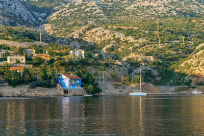 House by lake and buildings against mountain