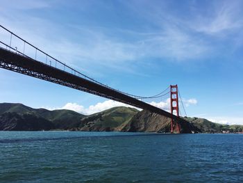 Low angle view of golden gate bridge over sea against blue sky