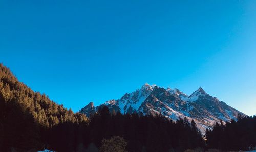 Scenic view of snowcapped mountains against clear blue sky