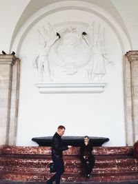 Full length portrait of young man standing against building
