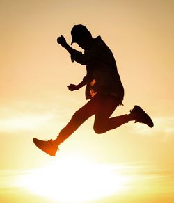 Silhouette of man jumping at sunset