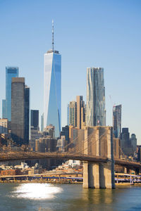 Freedom tower and brooklyn bridge against a clear blue sky in new york city