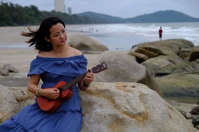 Young woman playing guitar on rocks