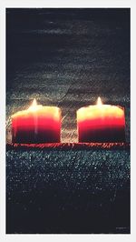 Lit candle in dark room