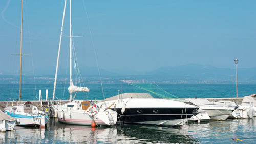 Sailboats moored in sea against clear sky