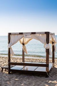 Chair on beach against clear sky