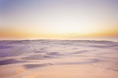 Scenic view of snow covered land against sky during sunset