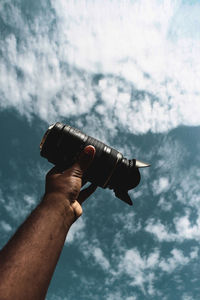 Close-up of man photographing against cloudy sky