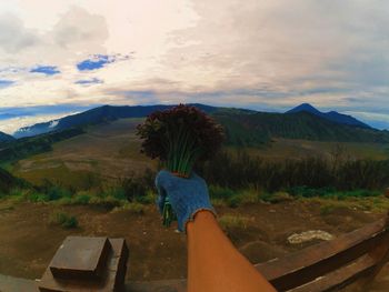 Person with umbrella on mountain against sky