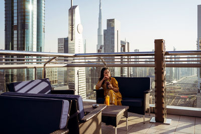 Woman standing on railing against buildings