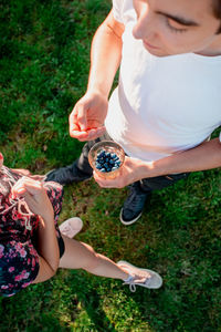 High angle view of siblings with blueberries in glass standing on field