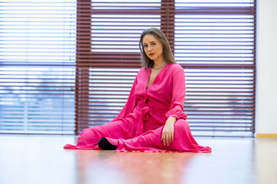 Portrait of young woman sitting on hardwood floor