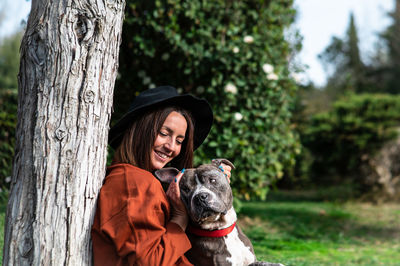 Woman with dog sitting by tree at park 