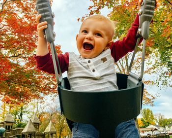 Cute toddler boy sitting on swing at park