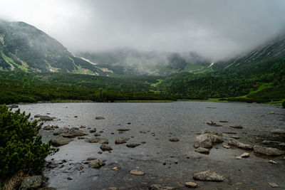 Scenic view of river by mountains against sky
