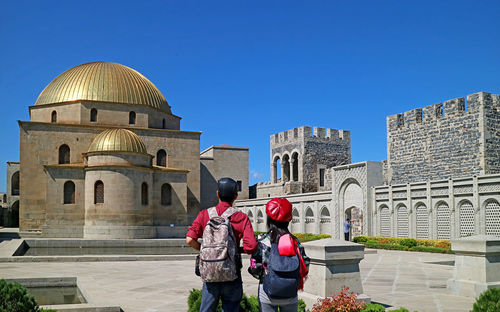 Rear view of man standing against historic building
