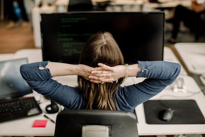 Rear view of entrepreneur sitting against computer at workplace